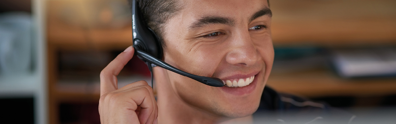 Ein Kundenberater telefoniert lächelnd mit einem Headset.